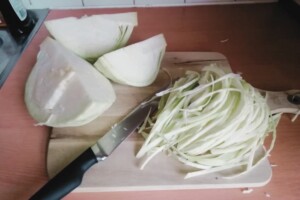 Using a knife to cut the cabbage into thin shreds.