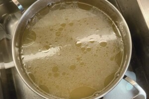 Allowing chicken stock to cool in the sink with cold water.