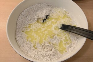 Melted butter together with dry ingredients for oat waffles in a bowl.