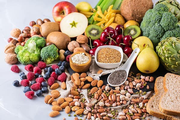 A variety of fiber-rich foods showcased on a table, including nuts, berries, fruits, vegetables, seeds, and more.