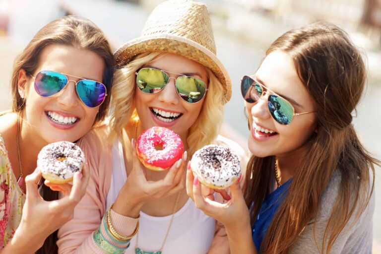 A group of friends indulges in donuts while out in the city, unaware of the health risks associated with consuming ultra-processed foods.