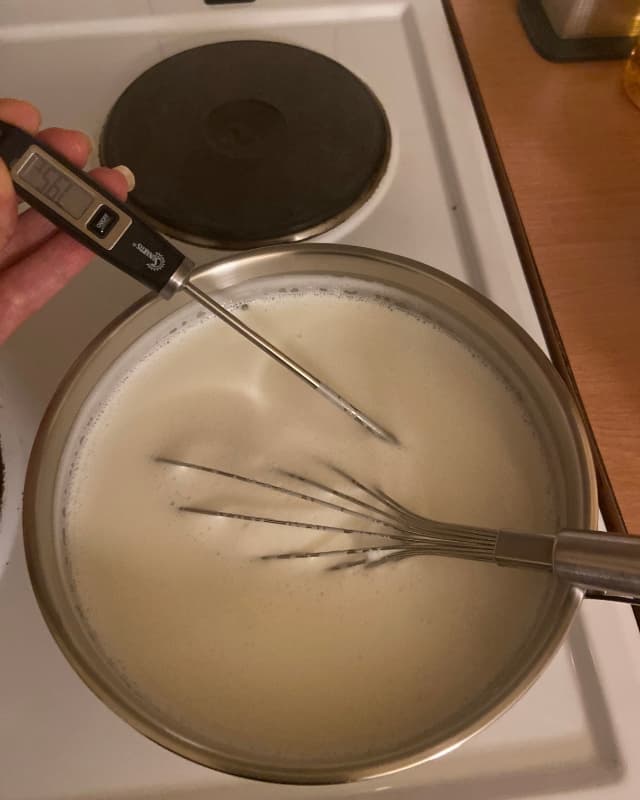 Using a thermometer to check the termperature of the milk.
