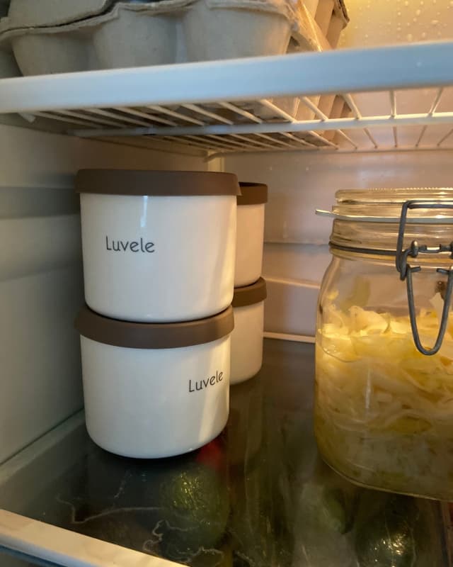 Four ceramic jars from Luvele filled with homemade yogurt are stacked neatly in the fridge.