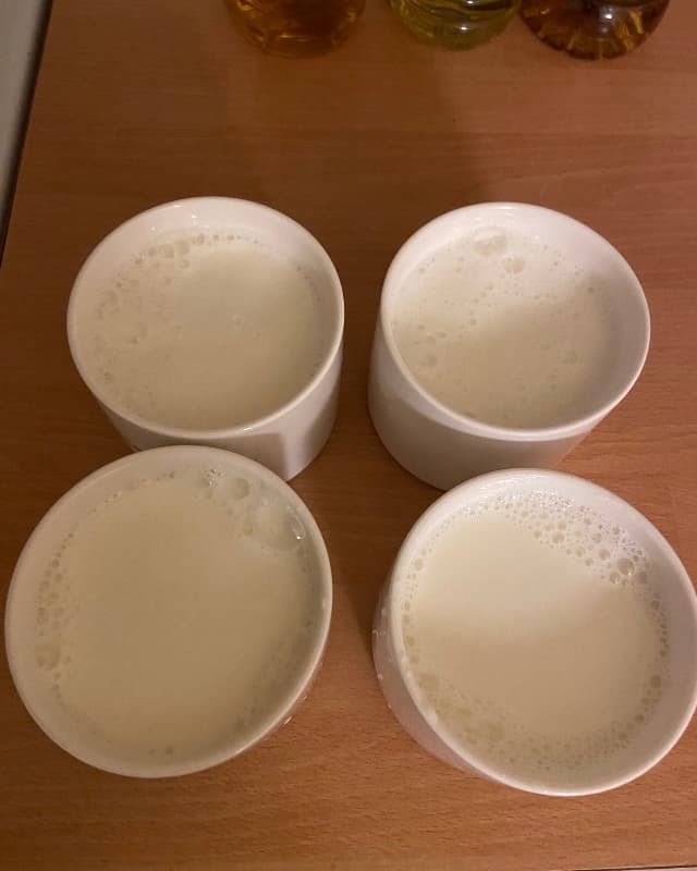 Milk with yogurt starter is poured into four ceramic jars.