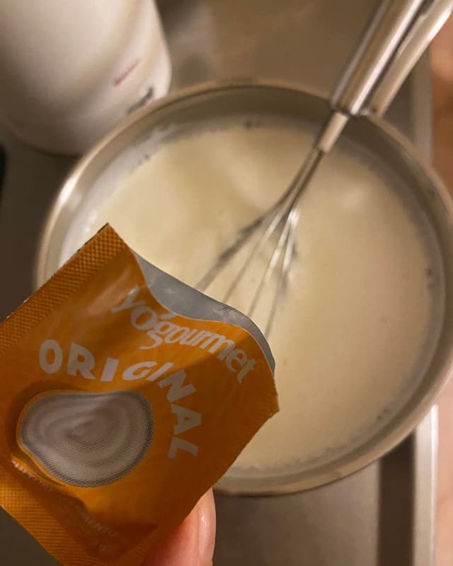 Yogourmet traditional yogurt starter is being poured into milk.