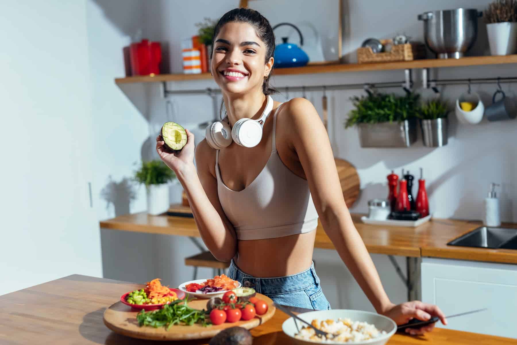 Health-conscious woman in kitchen preparing foods for gut health in a poke bowl.