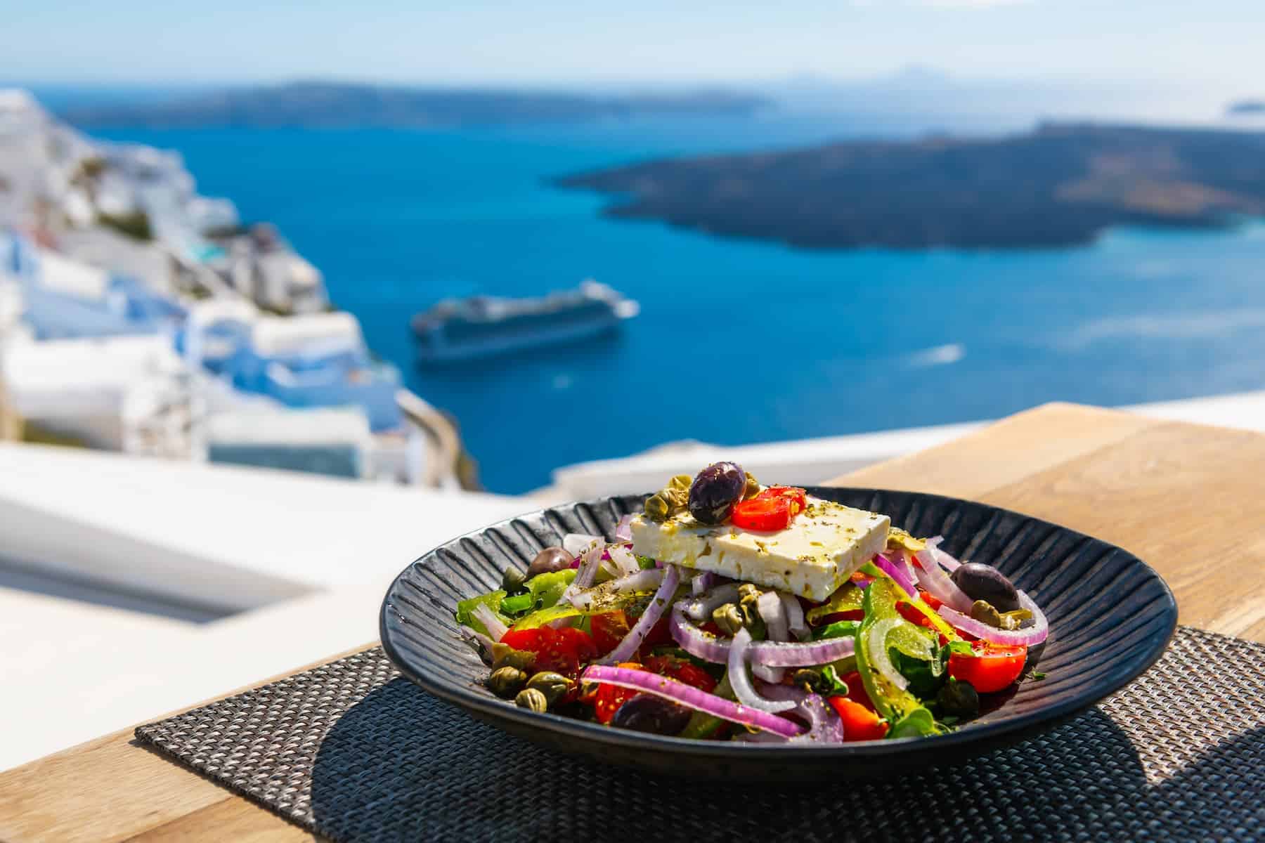 Fresh Greek salad of feta, tomatoes, onions, and olives served seaside, emphasizing Mediterranean diet benefits.