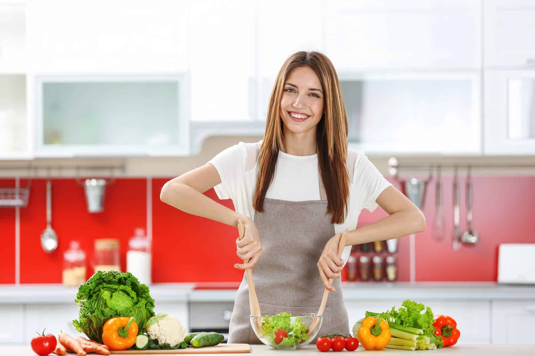 A woman in her kitchen is making a fresh salad, taking simple steps toward healthy eating.