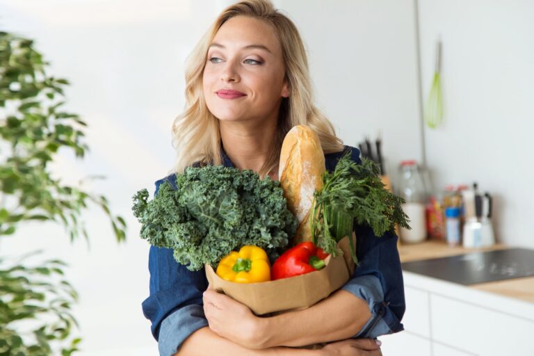 A woman in a blue shirt is holding a grocery bag filled with Mediterranean foods, having embraced the Mediterranean diet for a healthier lifestyle.