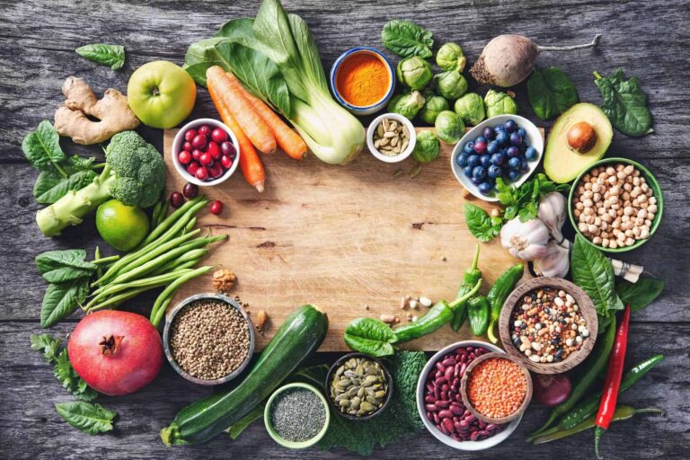 A variety of colorful fruits, vegetables, and grains arranged on a light brown cutting board, highlighting anti inflammation foods.