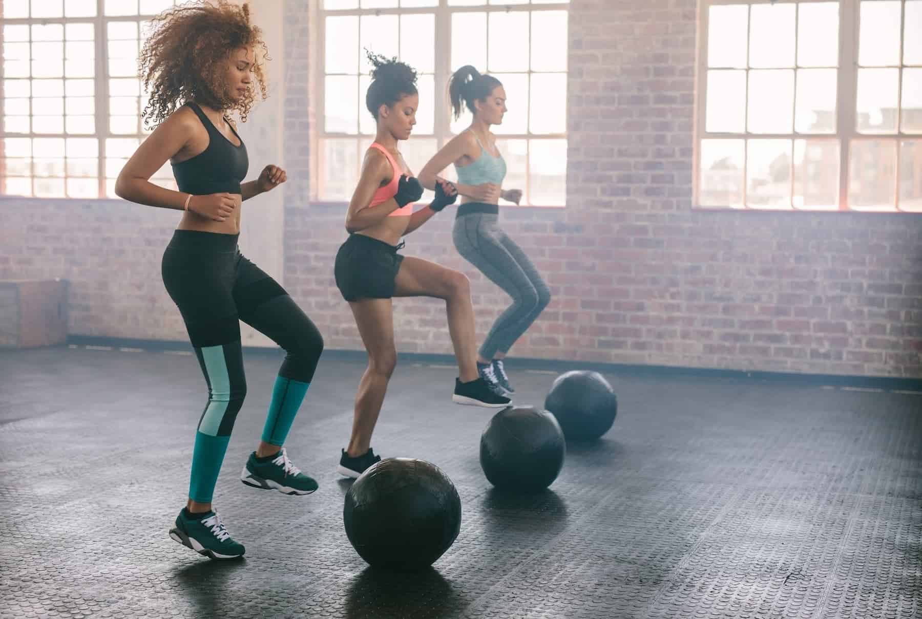 Women doing alternating toe-touch jumps on balls, showing fun exercise ideas for an enjoyable workout.