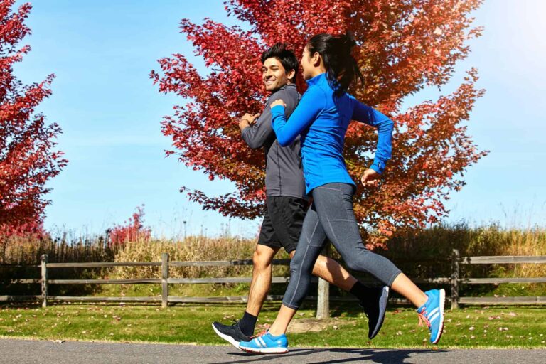 A smiling couple enjoys running together in a natural setting, illustrating a fun and healthy Valentine’s Day date idea.