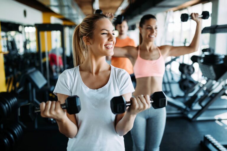 A small group of people enjoys light dumbbell exercises at the gym, highlighting friendly exercise for beginners.