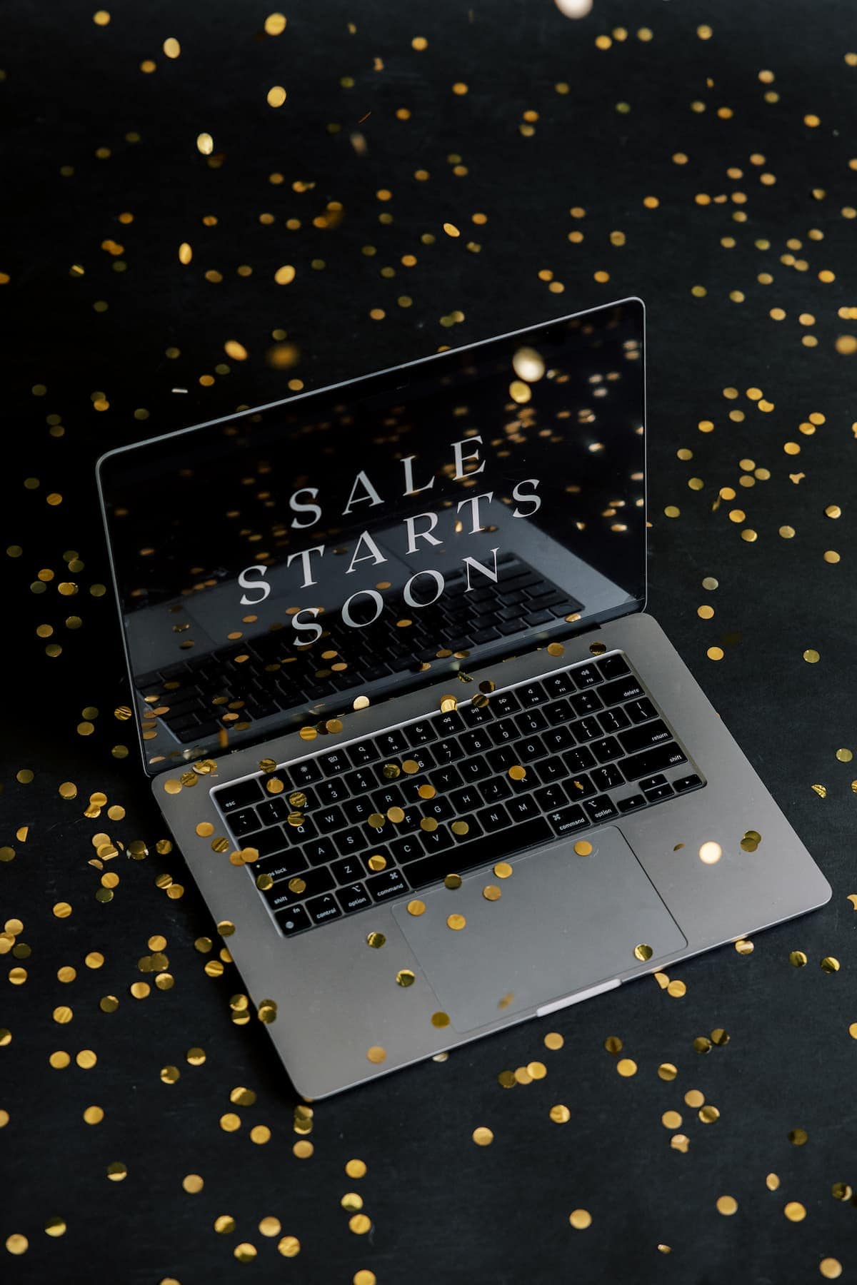 A laptop displaying "SALE STARTS SOON" surrounded by gold confetti on a black background highlighting Black Fridays deals for bloggers.