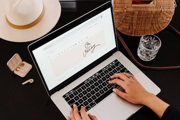 Woman typing on a laptop displaying ‘On Vacay,’ representing working remotely using the best email marketing platform.