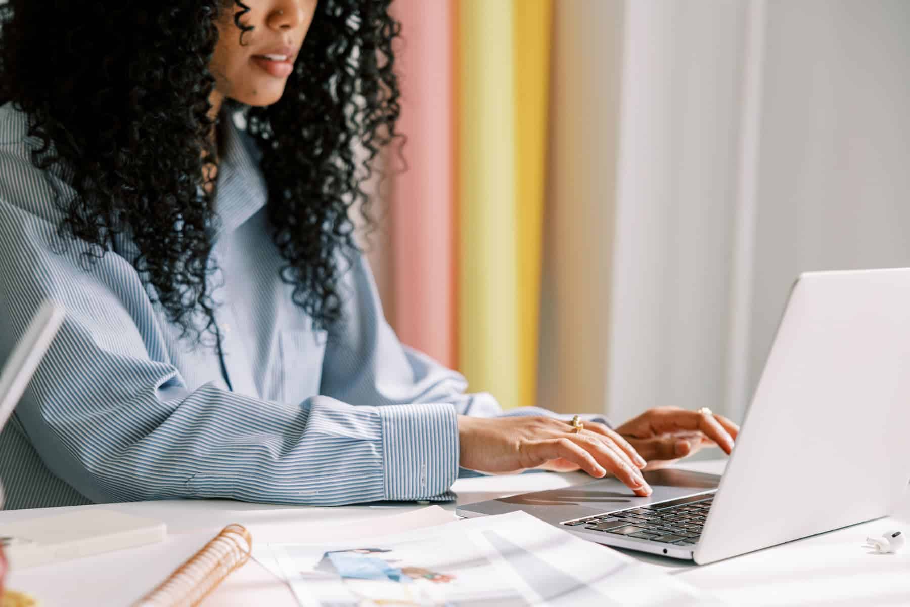 Woman working on a laptop at a desk with notes, using WP Rocket to improve website speed.