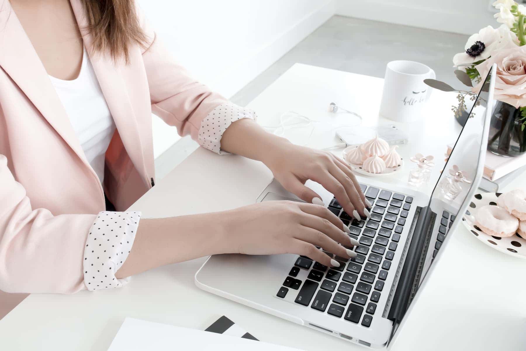 Woman working on her blog at a laptop with a styled workspace, symbolizing the use of premium WordPress themes.