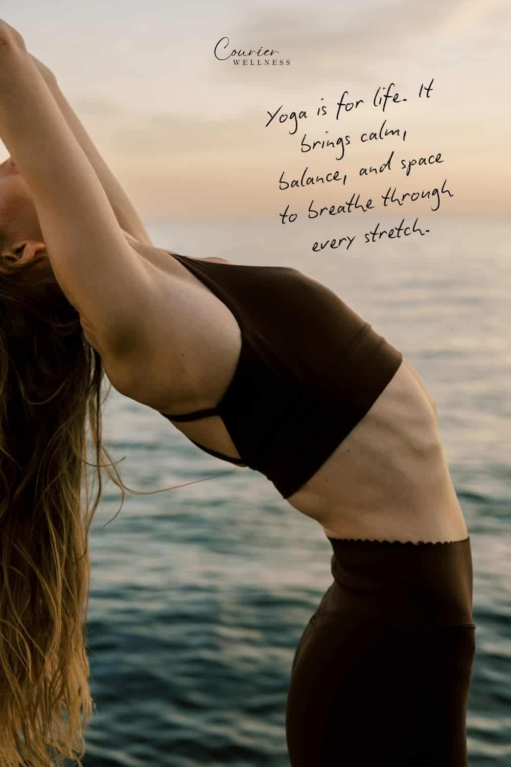Woman stretching with arms raised by the ocean at sunset, arching her back in a yoga pose.