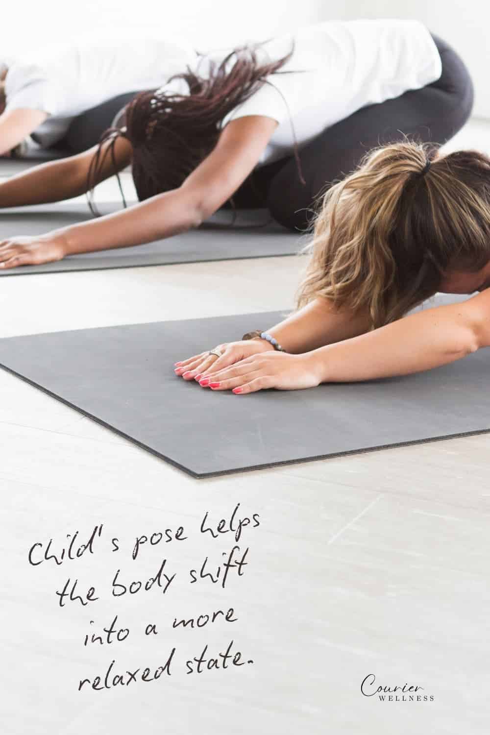 Three women practicing child’s pose together in a calm yoga studio.