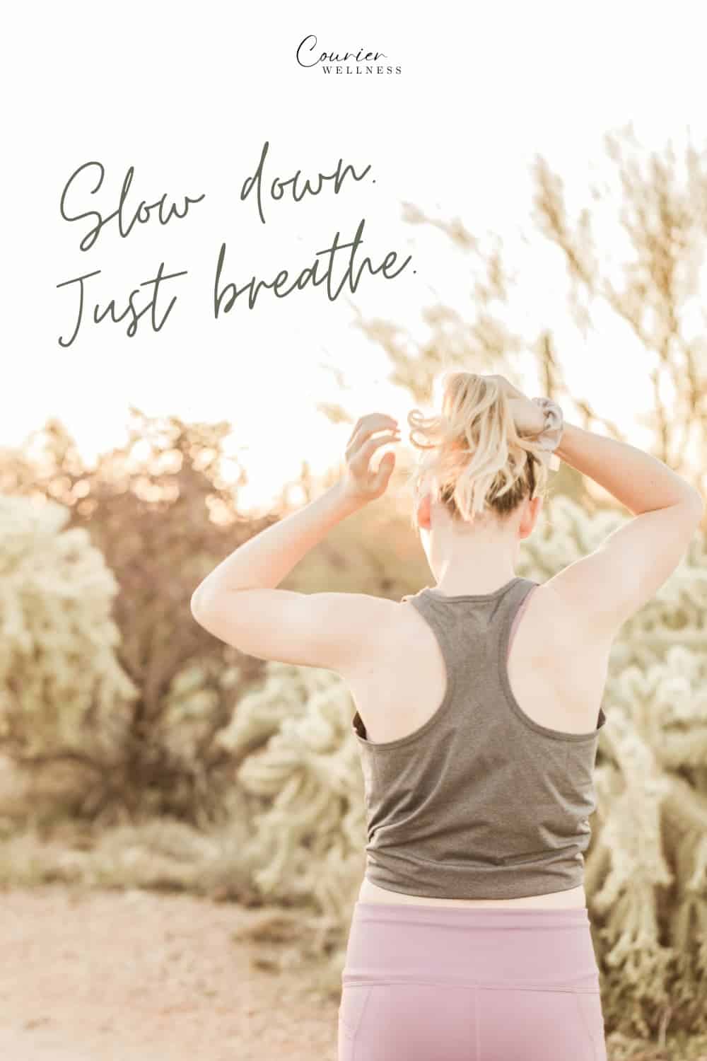 Woman walking through the desert tying her hair before starting a yoga session.