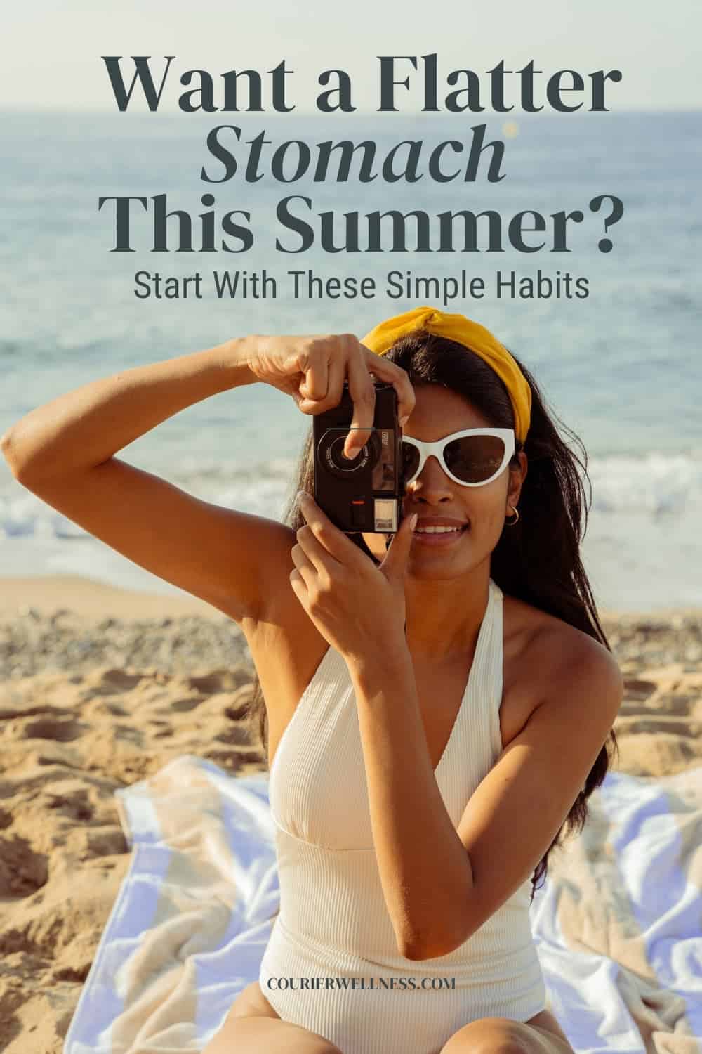 Woman in a white swimsuit and sunglasses sitting on a beach towel and taking a photo of the ocean on a sunny summer day.